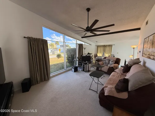 a living room with furniture a ceiling fan and a large window