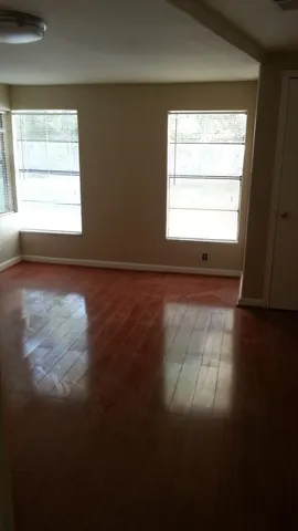 a view of an empty room with wooden floor and a window