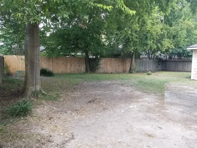 a view of a yard with a tree and wooden fence