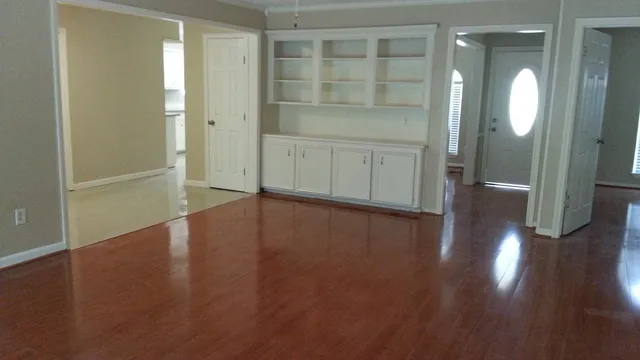 an empty room with wooden floor and mirror