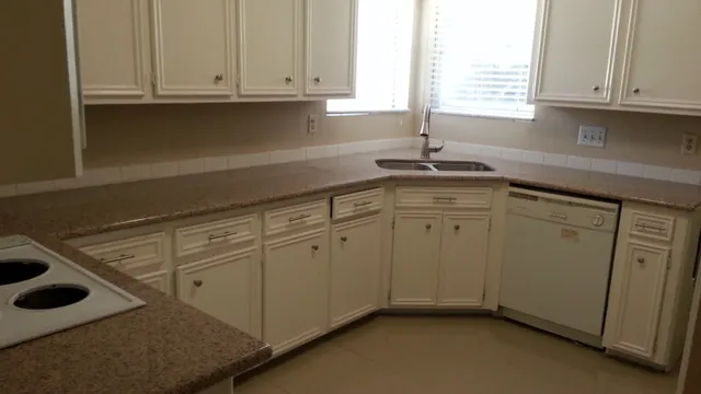 a kitchen with white cabinets sink and window