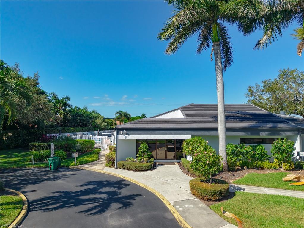 729 Landover Court, Unit 102 Naples, FL 34104 - Photo 27 of 28 a view of a garden with a table under an umbrella