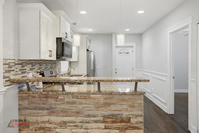 a view of a kitchen with kitchen island a sink stainless steel appliances and cabinets