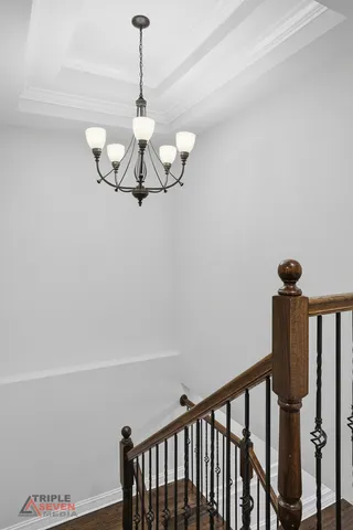 a view of a hallway with chandelier fan and wooden floor