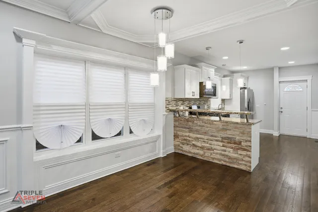 a kitchen with kitchen island a counter top space a large window and stainless steel appliances