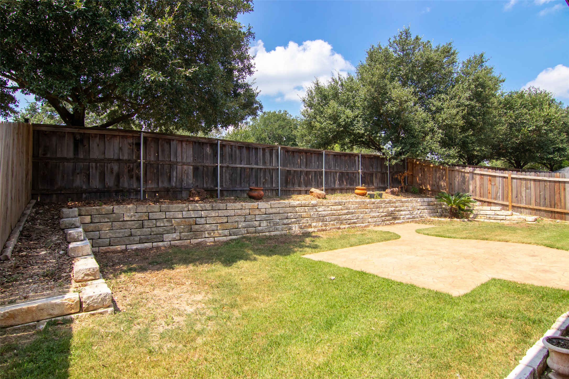 12104 Broten Street Austin, TX 78748 - Photo 30 of 32 A tiered backyard retreat, featuring a well-maintained lawn and sturdy stone retaining walls for outdoor enjoyment.