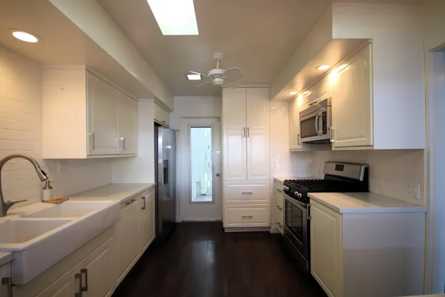 a kitchen that has a sink a stove and cabinets
