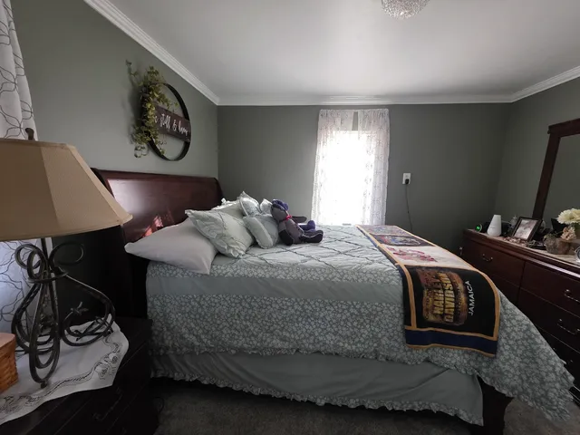 a bedroom with a bed and a lamp on dresser