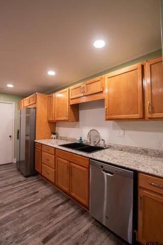 a kitchen with stainless steel appliances granite countertop a sink a stove and a wooden floors