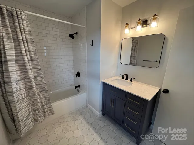 a bathroom with a sink vanity granite tub shower and a mirror