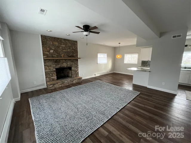an empty room with wooden floor a fireplace and windows