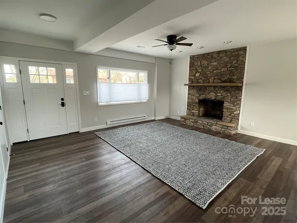 an empty room with wooden floor fireplace and windows