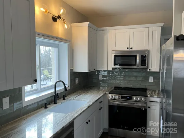 a kitchen with stainless steel appliances granite countertop a stove a sink and a microwave