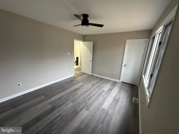 a view of a hallway with white cabinets and wooden floor