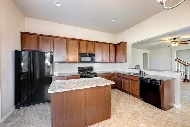 a kitchen with stainless steel appliances granite countertop a sink stove refrigerator and cabinets