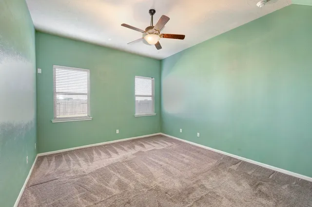 an empty room with a window and a ceiling fan