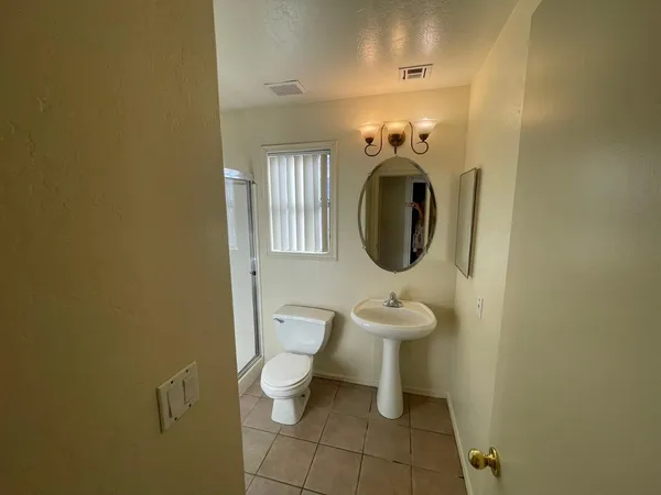 an empty room with a chandelier fan and windows