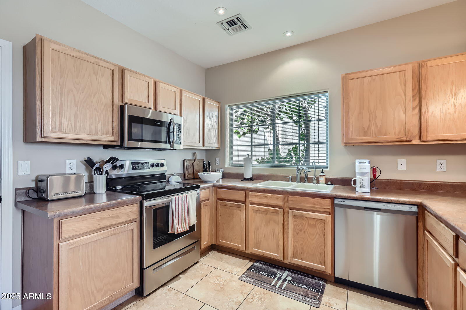 2801 North Litchfield Road, Unit 65 Goodyear, AZ 85395 - Photo 9 of 30 a kitchen with stainless steel appliances granite countertop a sink a stove a refrigerator cabinets and a window