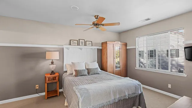 a sign that is sitting in front of a house with plants and a yard