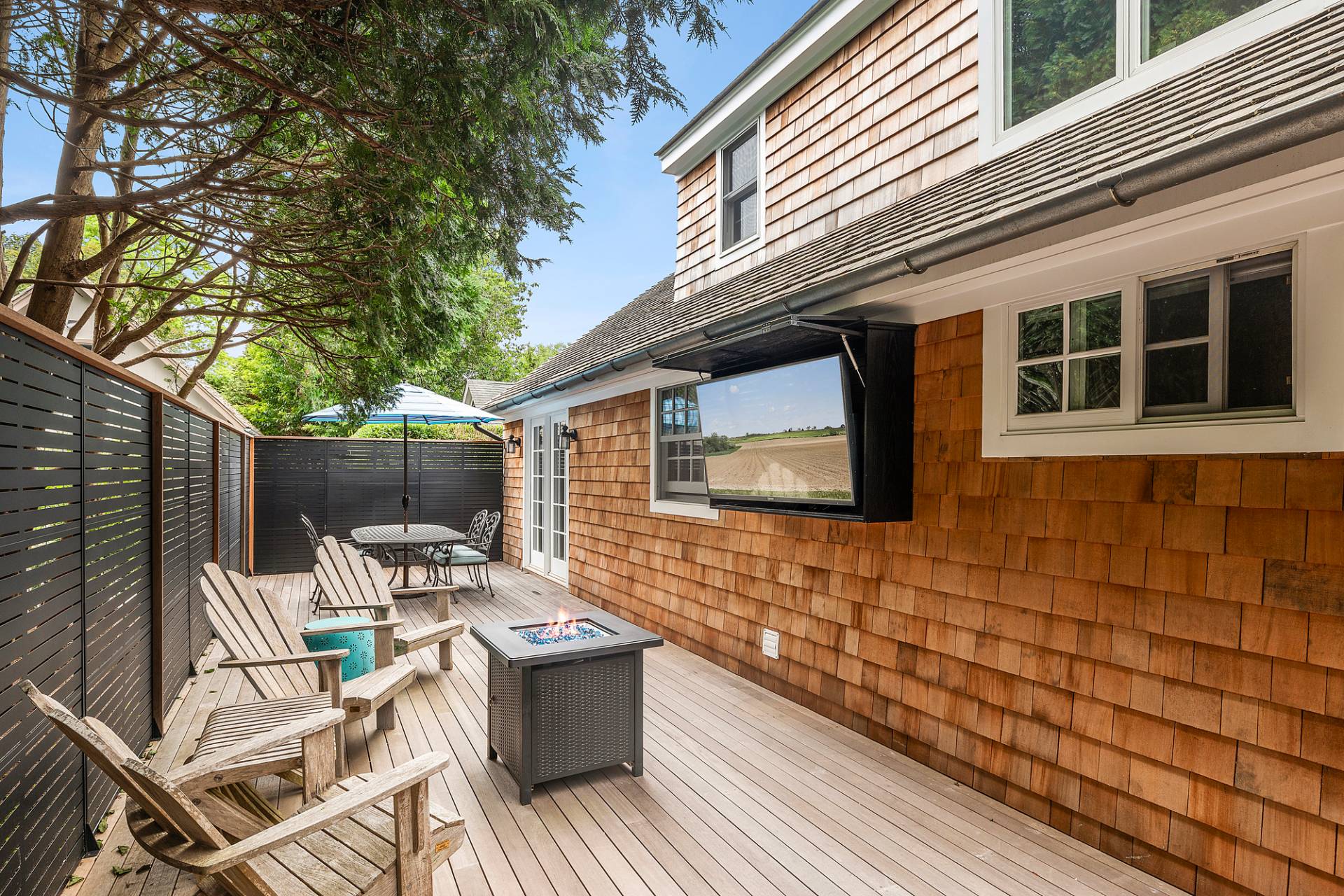 50 Sherrill Road East Hampton, NY 11937 - Photo 19 of 20 a view of a patio with table and chairs with wooden floor and fence