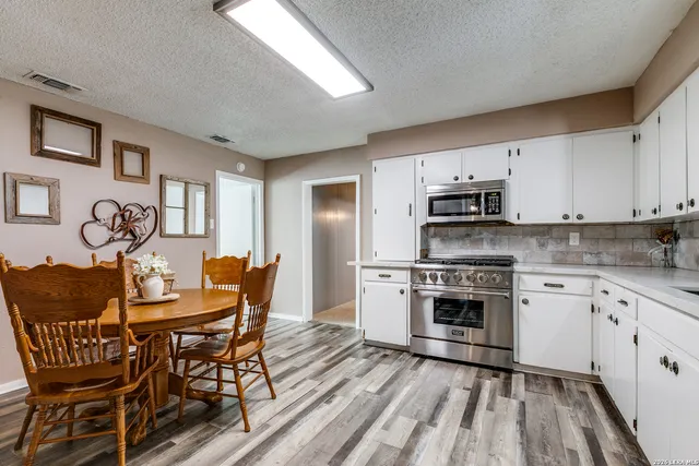 a kitchen with stainless steel appliances granite countertop a dining table chairs and granite counter tops