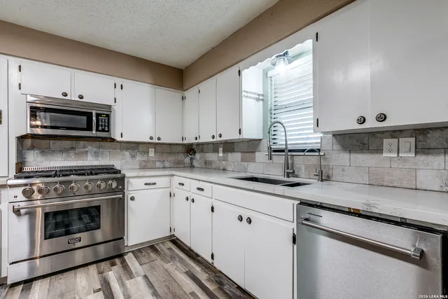 a kitchen with granite countertop white cabinets white stainless steel appliances and a sink