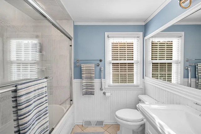 a bathroom with a sink a toilet a mirror and a window