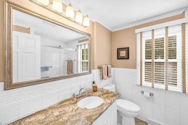 a bathroom with a granite countertop sink mirror and a toilet