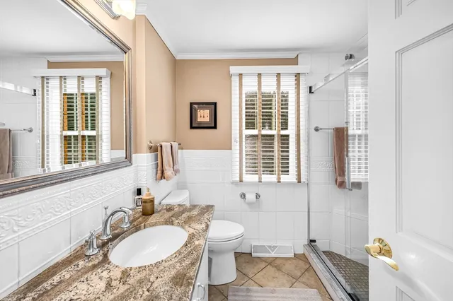 a bathroom with a granite countertop sink toilet a mirror and next to a window