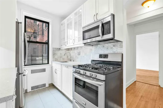 a kitchen with stainless steel appliances granite countertop white cabinets a stove top oven a sink and dishwasher