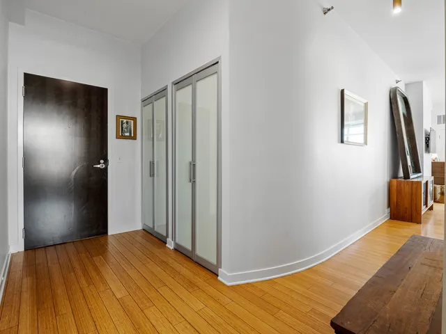 a view of a hallway with wooden floor and a bathroom