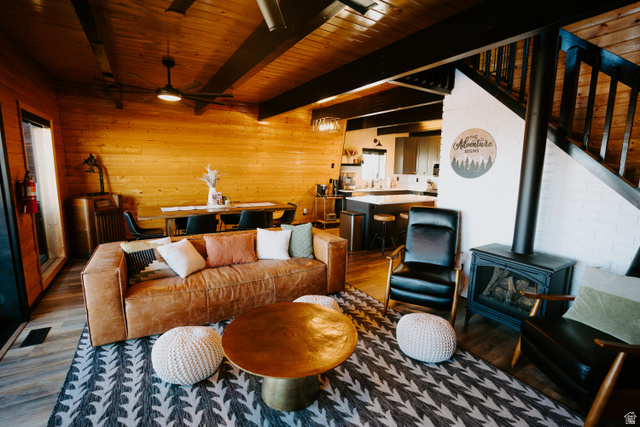 1413 Basel Drive Midway, UT 84049 - Photo 4 of 137 Living area featuring a wood stove, wood finished floors, wood walls, a wooden ceiling with exposed beams, and ceiling fan