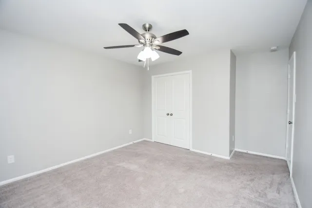 an empty room with a window and a fan