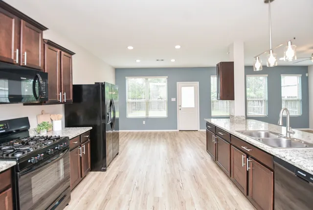 a large kitchen with stainless steel appliances granite countertop a lot of counter space and wooden floor