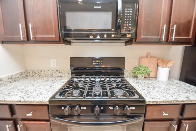 a kitchen with granite countertop a stove and a white wooden cabinets