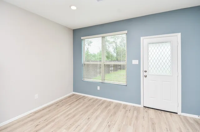 a view of an empty room with wooden floor and a window