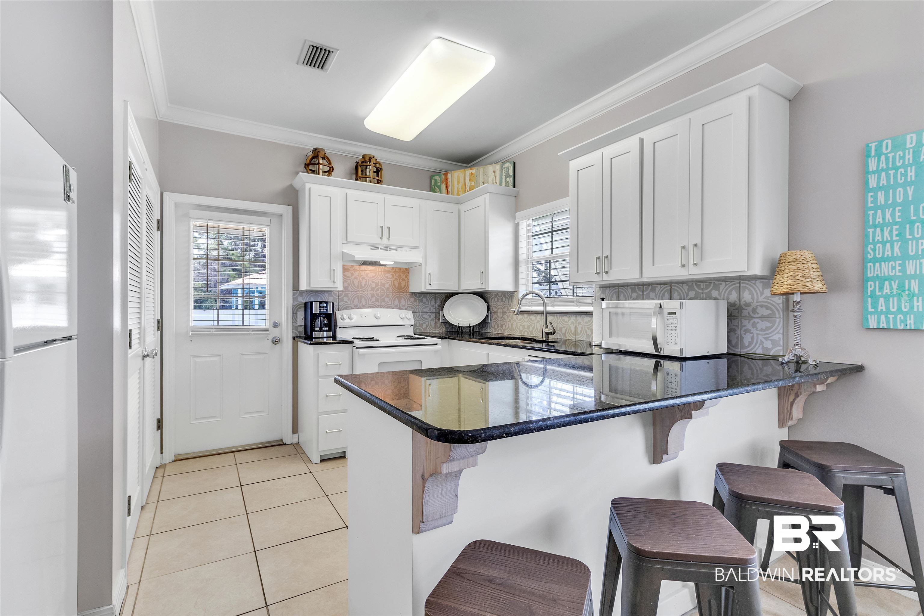 4324 B Lindsey Lane, Unit 4324B Orange Beach, AL 36561 - Photo 2 of 33 Kitchen with light tile patterned floors, a sink, a peninsula, white appliances, and under cabinet range hood