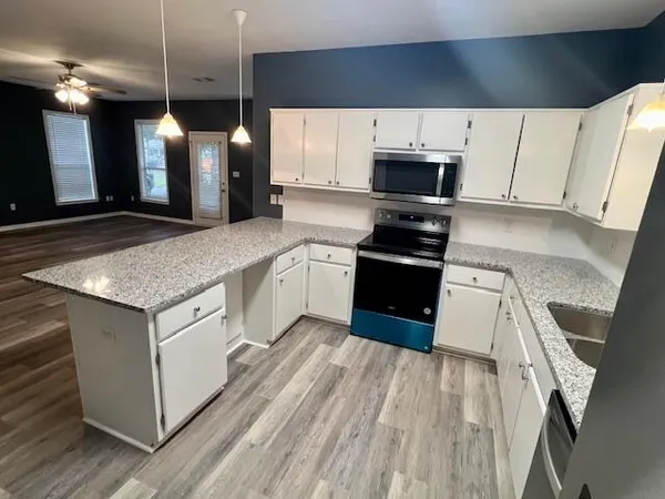 a kitchen with stainless steel appliances granite countertop a stove a sink and a microwave