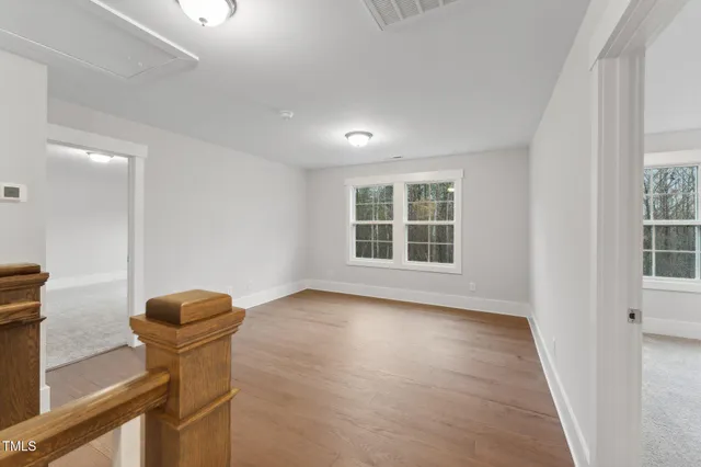 a view of an empty room with a window and wooden floor
