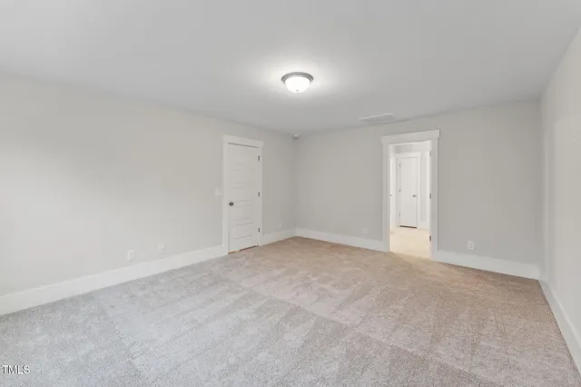 a view of an empty room and chandelier fan