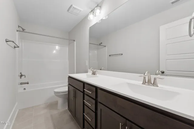 a bathroom with a double vanity sink toilet mirror and bathtub