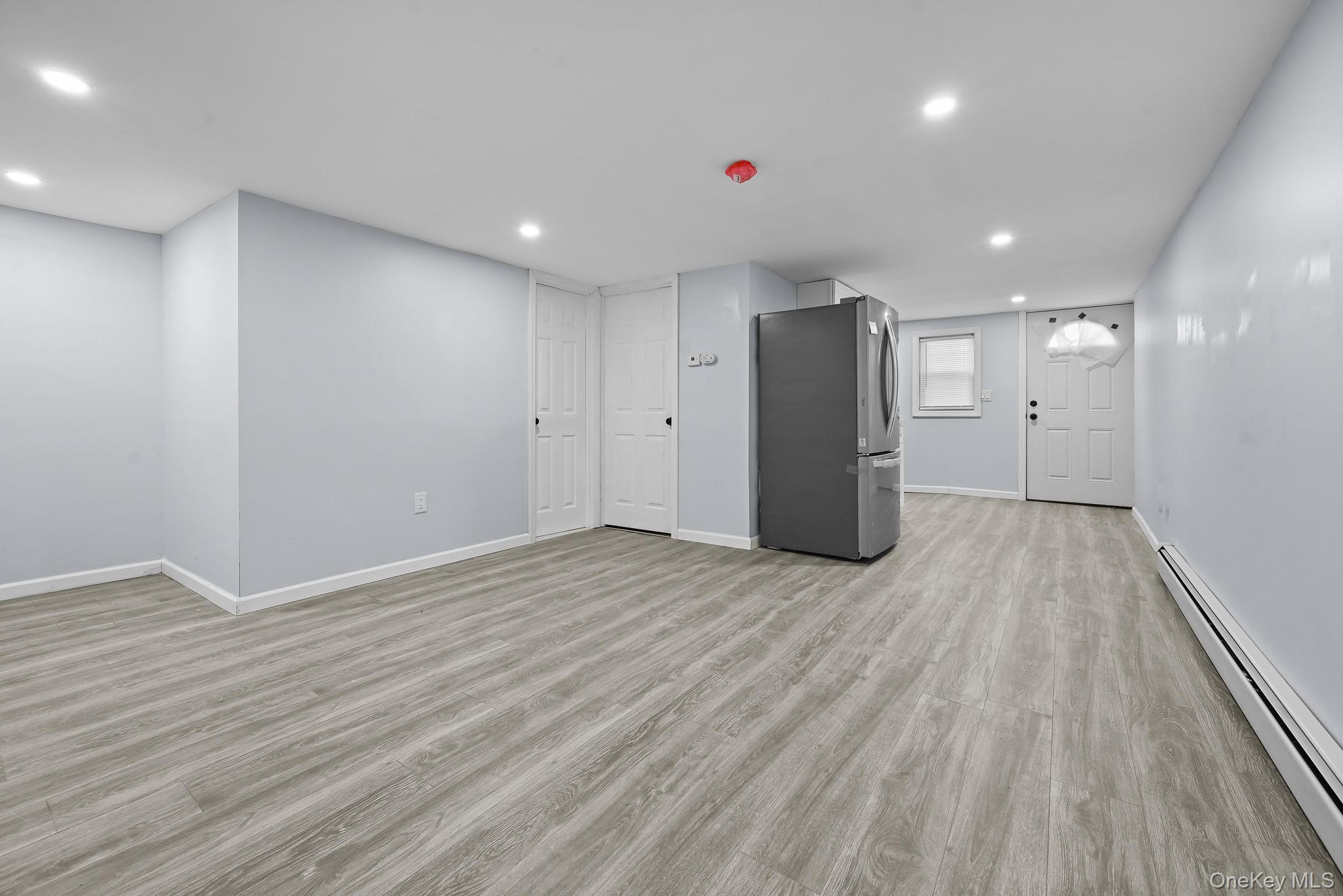 90-04 24th Road Queens, NY 11369 - Photo 12 of 20 Unfurnished living room featuring a baseboard heating unit, light wood finished floors, and recessed lighting
