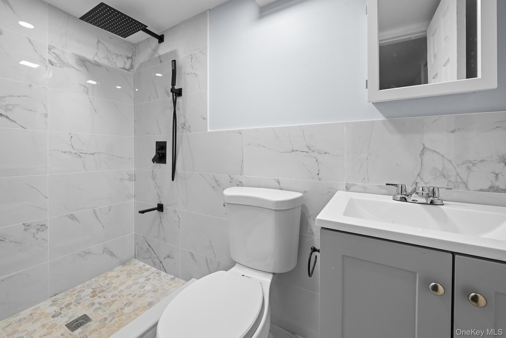 90-04 24th Road Queens, NY 11369 - Photo 16 of 20 Bathroom with a marble finish shower, vanity, and tile walls