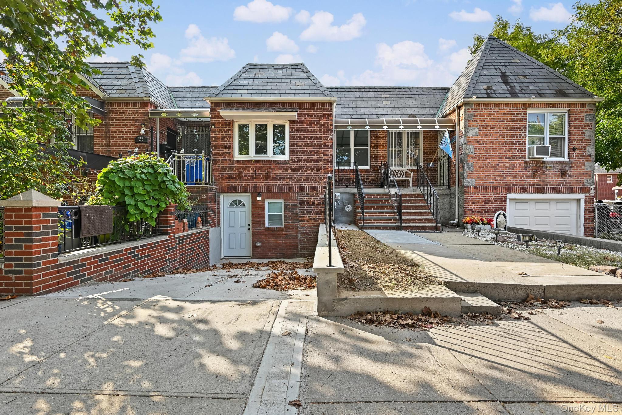90-04 24th Road Queens, NY 11369 - Photo 2 of 20 View of front facade with brick siding, a high end roof, and concrete driveway