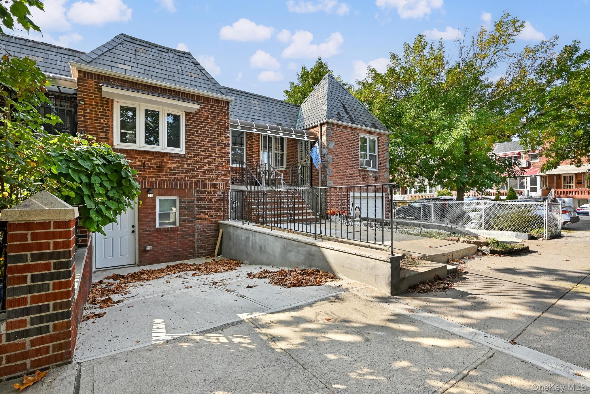 90-04 24th Road Queens, NY 11369 - Photo 4 of 20 Rear view of property featuring a high end roof, brick siding, and a fenced front yard