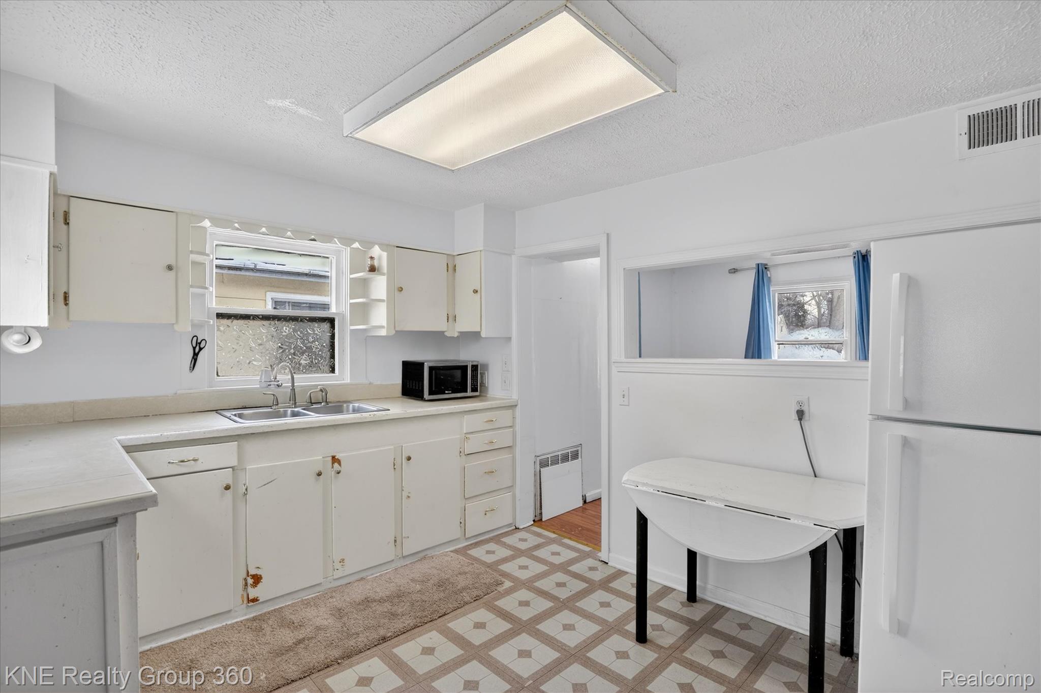 4928 Hughes Road Lansing, MI 48910 - Photo 17 of 35 Kitchen featuring light countertops, freestanding refrigerator, a textured ceiling, open shelves, and plenty of natural light
