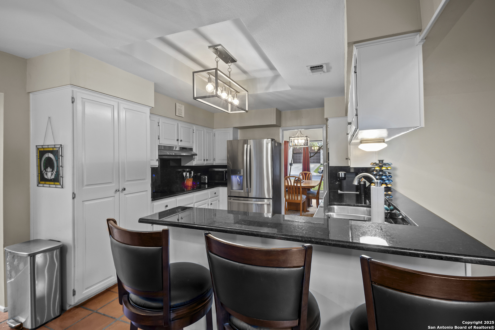 12907 Kings Forest Street San Antonio, TX 78230 - Photo 11 of 44 a kitchen with stainless steel appliances granite countertop a dining table chairs and a refrigerator