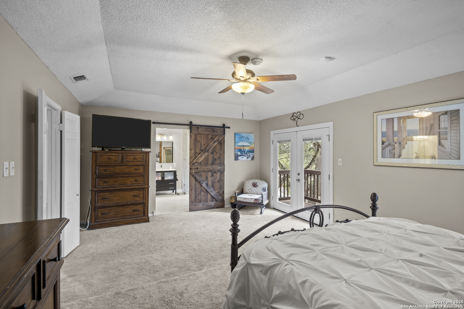 12907 Kings Forest Street San Antonio, TX 78230 - Photo 21 of 44 a spacious bedroom with a bed and a flat tv screen on the dresser