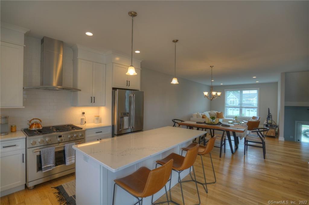 46 Park Avenue, Unit 46 Mystic, CT 06355 - Photo 4 of 28 a kitchen with stainless steel appliances granite countertop a stove a refrigerator a kitchen island a dining table and chairs with wooden floor