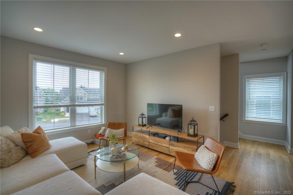 46 Park Avenue, Unit 46 Mystic, CT 06355 - Photo 10 of 28 a living room with furniture a flat screen tv and a floor to ceiling window